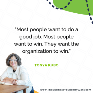 Tonya leans over a desk while wearing her favorite white denim jacket next to a quote, which reads, "Most people want to do a good job. Most people want to win. They want the organization to win."